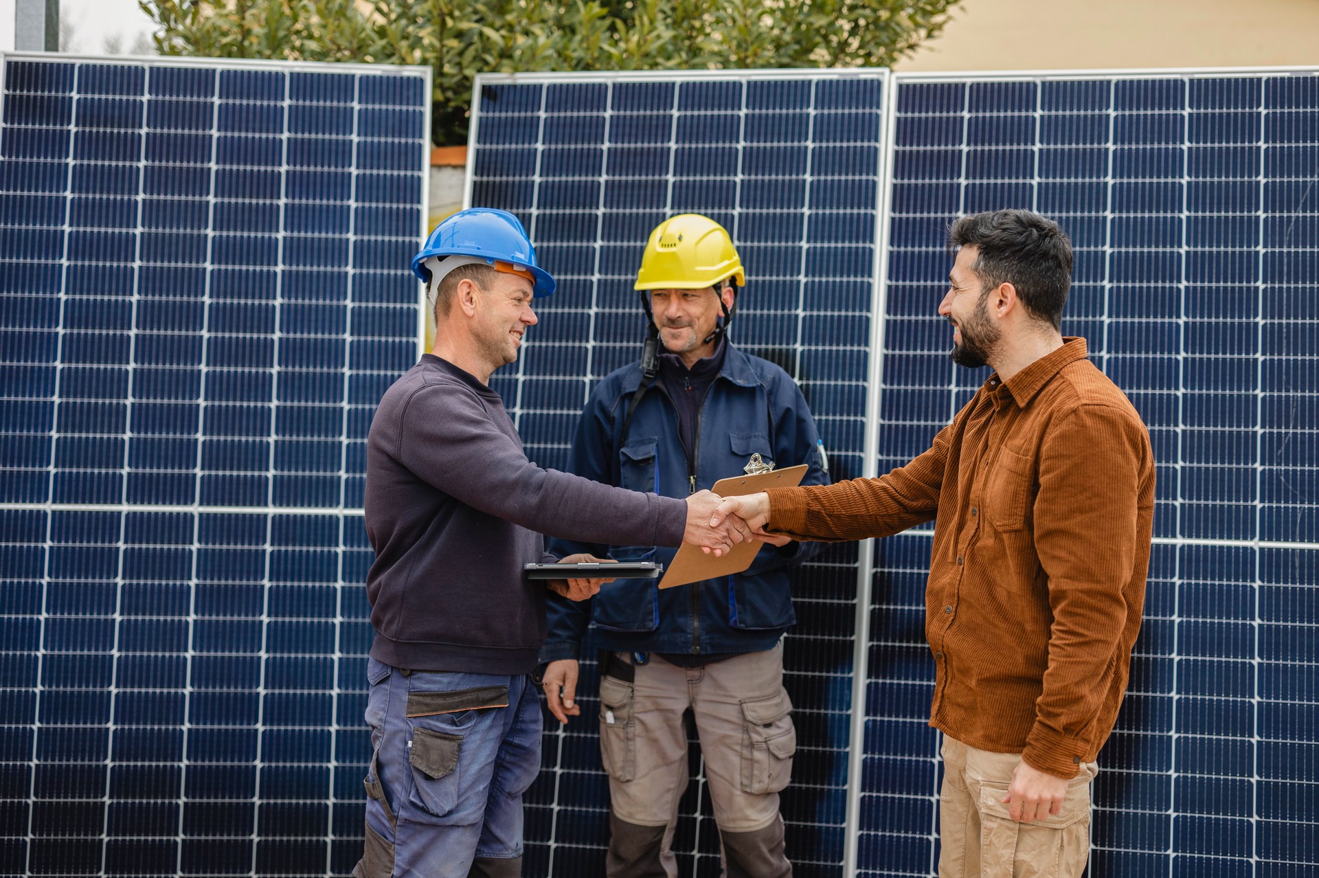 Engineers shaking hands with customer after installing solar panels
