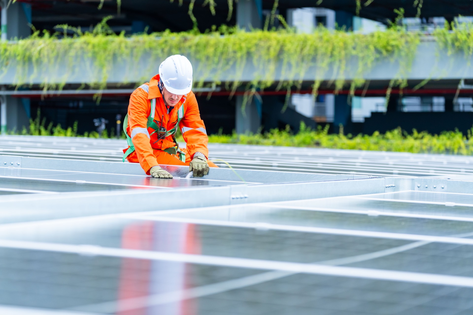 Male engineer maintaining solar cell panels on building rooftop.