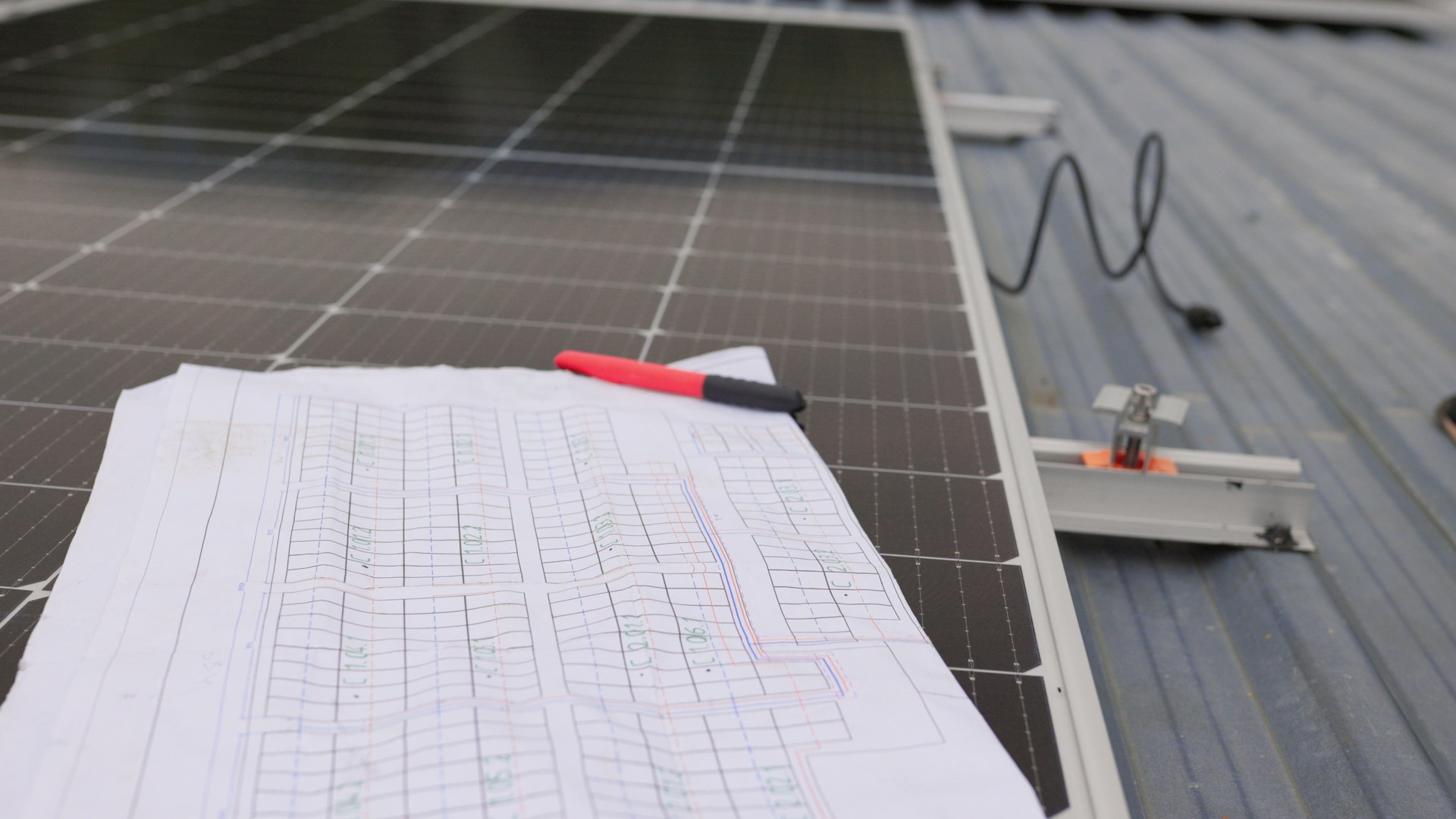Close up of worker installing and working on maintenance of photovoltaic panel system installed. In the foreground is a diagram of the installation of solar panels. Solar panels on roof top.